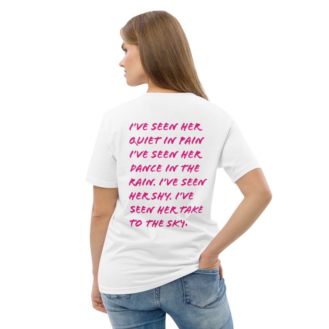 A female standing with her back towards the camera, with a text on her t-shirt saying: I've seen her in pain. I've seen her dance in the rain. I've seen her shy. I've seen her take to the sky.